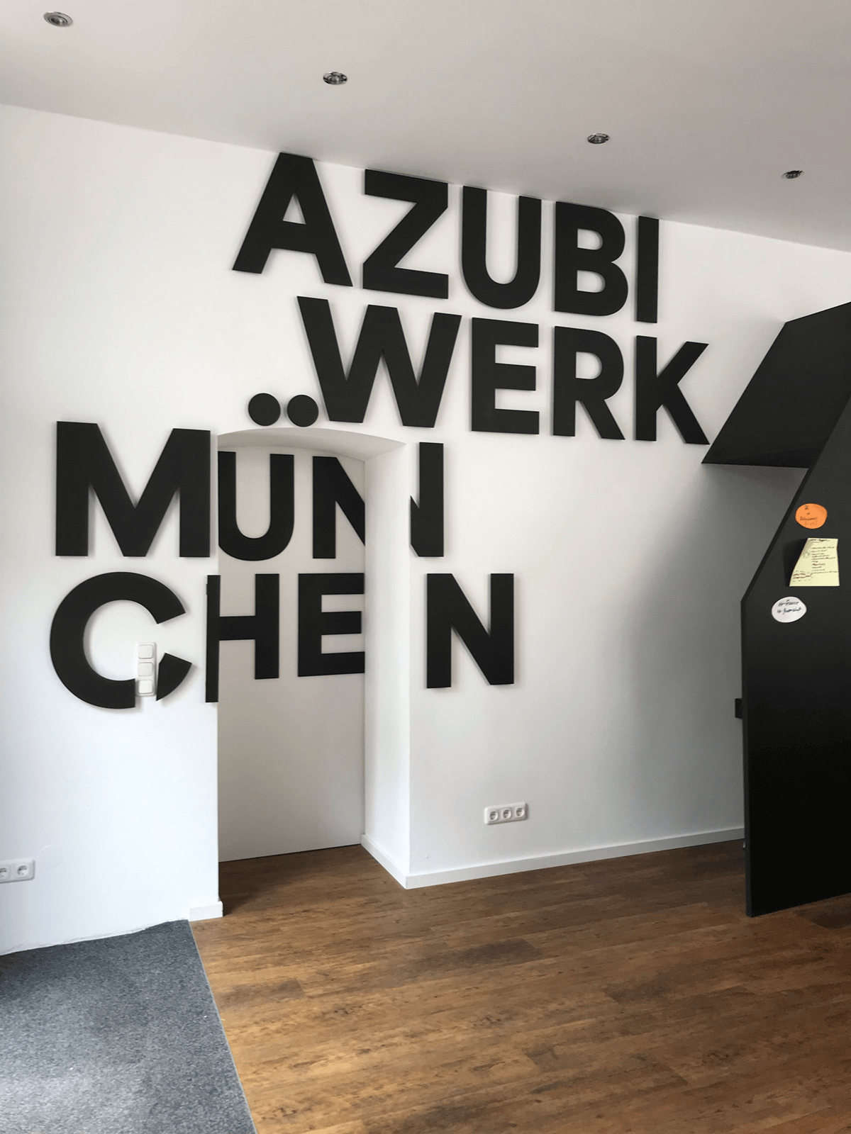 Büroraum mit dem Schriftzug "Auzbiwerk München" an der Wand